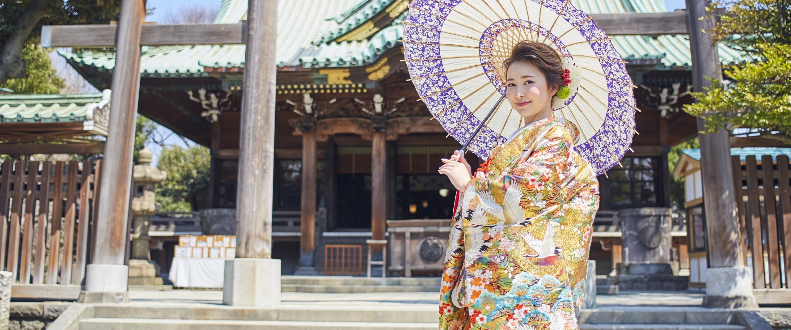 牛嶋神社の前に立ち和傘をさす着物姿の花嫁