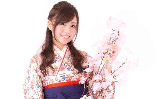 桜の枝を手にしている笑顔の袴姿の女学生