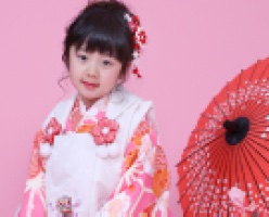 番傘を横に座る着物姿の3歳女児